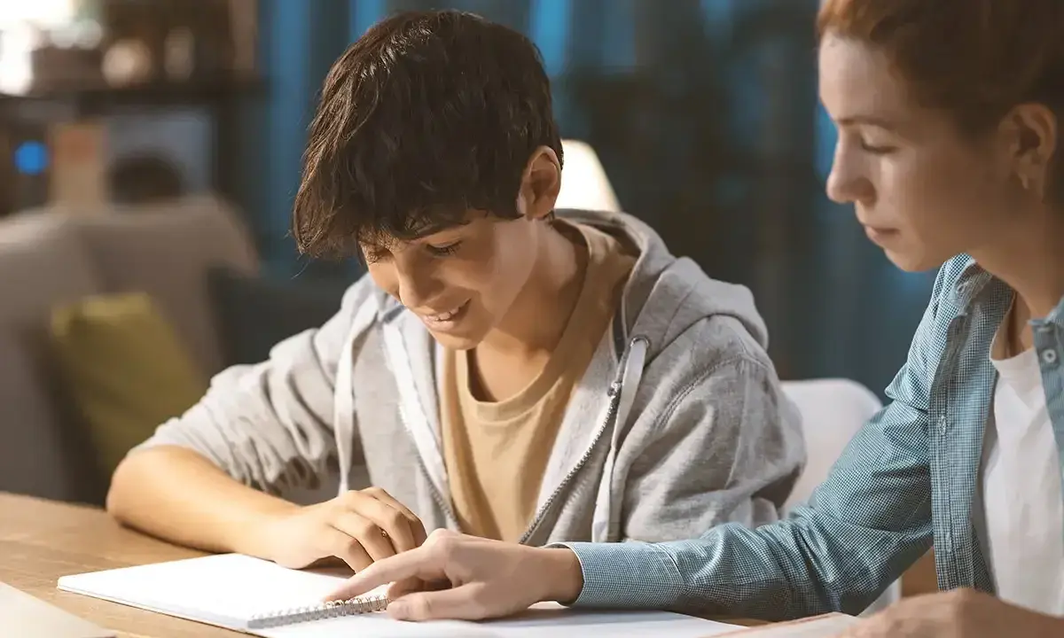 Ein Schüler gibt einem jüngeren Jungen Nachhilfe. Beide sind konzentriert und lernen gemeinsam.
