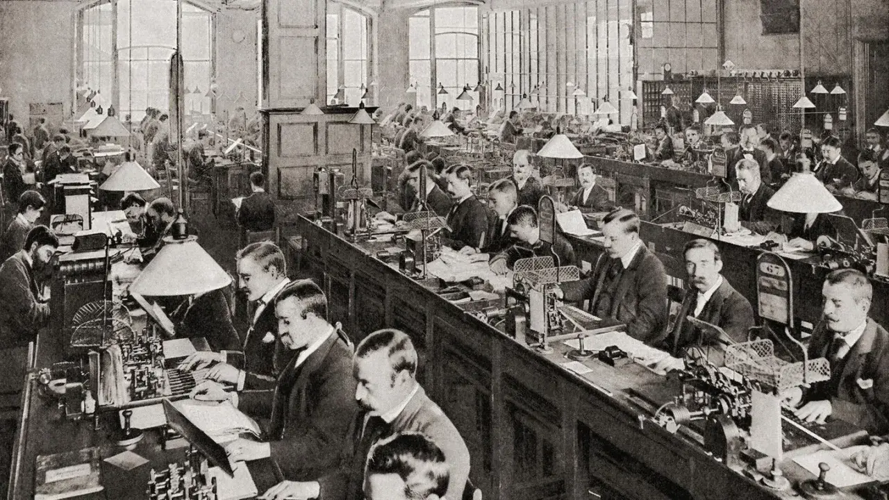 Männer arbeiten in einem Großraumbüro mit vielen Schreibtischen und Lampen. Die Szene zeigt die Arbeitsbedingungen der Industrialisierung.