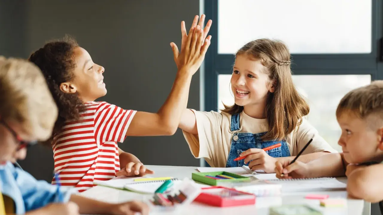 Kinder geben sich beim Lernen die Hand. Sie arbeiten an verschiedenen **Gruppenarbeit Methoden** und zeigen Freude am gemeinsamen Erfolg.