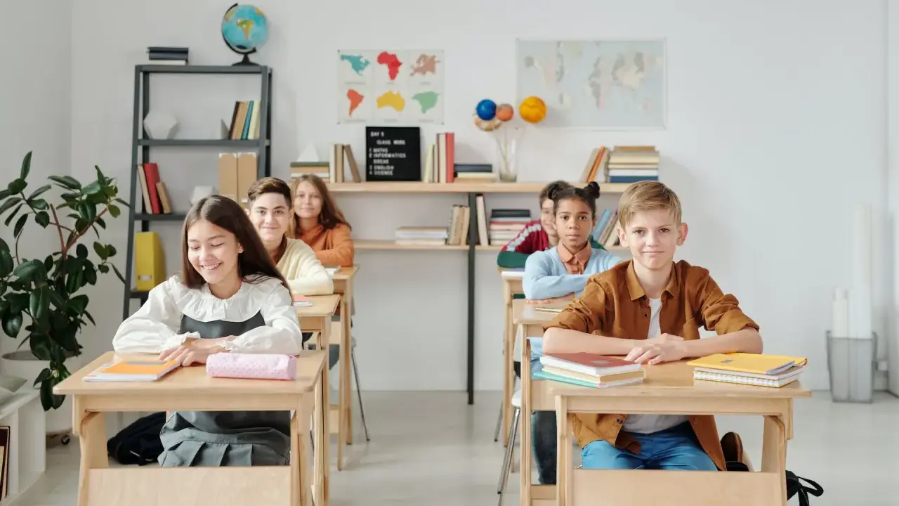 Schüler sitzen an Holztischen in einem hellen Klassenzimmer. Eine mögliche Sitzordnung für unruhige Klassen, die Konzentration fördert.