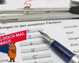 Zeugnis mit Noten in Worten. Ein Zirkel und ein Füller liegen auf dem Blatt. Die Maus fragt: "Frag doch mal die Maus".