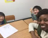 Fröhliche Kinder lernen Englisch. Eine Lehrerin gibt Nachhilfe auf Englisch.