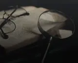 Brille und Lupe über einem alten Buch, bereit für eine tiefgehende Gedichtanalyse.