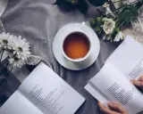 Eine Tasse Tee, Blumen und ein Buch mit einem wehmütigen Gedicht.