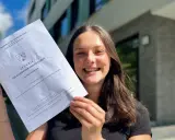 Stolze Schülerin mit Abiturzeugnis in der Hand. Sie fragt sich, wie viele Punkte für 0,9 Abi nötig sind.