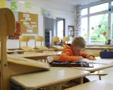 Ein Junge lernt allein im Klassenzimmer. Die leeren Stühle erinnern an eine kollektivstrafe, die er nicht verdient hat.