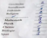Schulzeugnis mit Fächern wie Mathematik, Physik, Chemie, Biologie und Sport. Die Noten sind teilweise unleserlich, aber eine 7-Punkte-Note ist erkennbar.