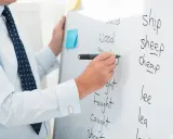 Lehrer schreibt englische Wörter an Tafel, um vokabeln lernen methoden zu demonstrieren.