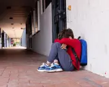 Ein Junge sitzt traurig in einem Schulflur, den Kopf in den Armen vergraben. Er fühlt sich allein, als ob mein Kind gemobbt wird und der Lehrer nichts tut.