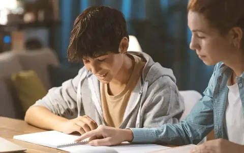 Ein Schüler gibt einem jüngeren Jungen Nachhilfe. Beide sind konzentriert und lernen gemeinsam.