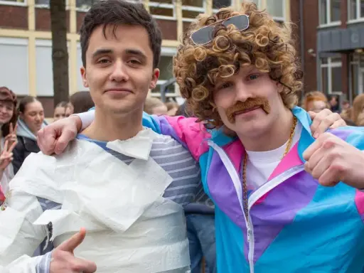 Zwei Schüler feiern die zeitreise mottowoche. Einer ist in Klopapier gewickelt, der andere trägt eine Perücke und einen Schnurrbart.