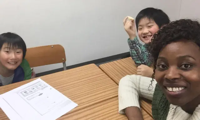 Fröhliche Kinder lernen Englisch. Eine Lehrerin gibt Nachhilfe auf Englisch.