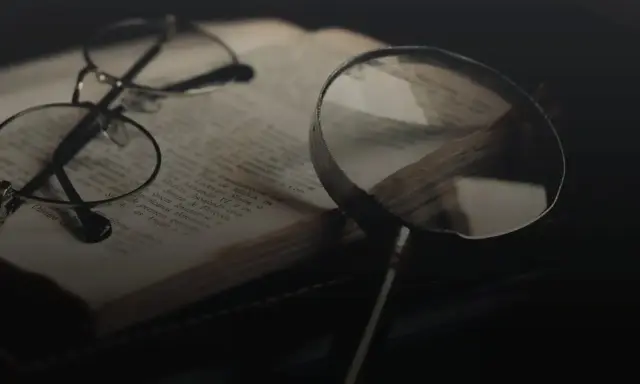 Brille und Lupe über einem alten Buch, bereit für eine tiefgehende Gedichtanalyse.