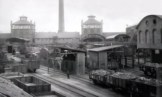 Ein Zeugnis der **hochindustrialisierung**: Zollverein II mit Schornstein, Loren voller Kohle und Holzlager.