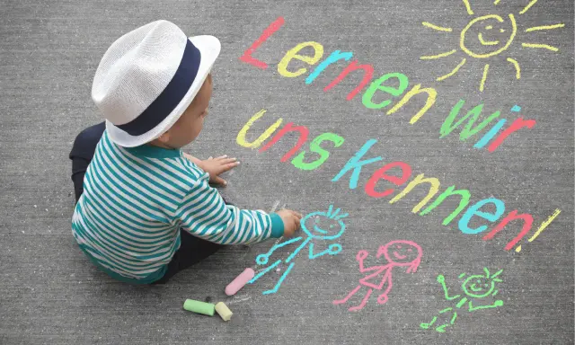 Kleiner Junge mit Hut malt mit Kreide auf Asphalt. Namensspiele für Kinder: "Lernen wir uns kennen!" mit Sonne und Figuren.