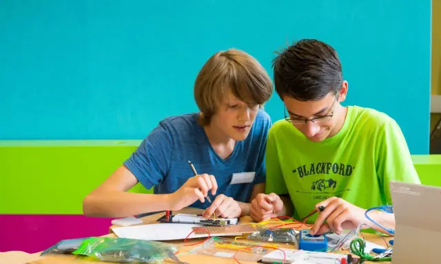 Zwei Jungen arbeiten konzentriert an einem Elektronikprojekt. Sie nutzen kreative Methoden der Gruppenarbeit, um ihre Ideen umzusetzen.