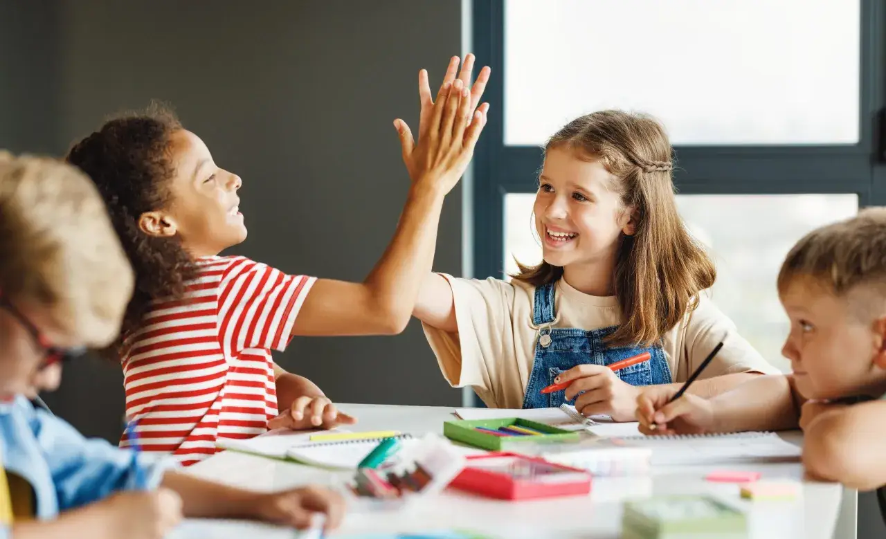 Kinder geben sich beim Lernen die Hand. Sie arbeiten an verschiedenen **Gruppenarbeit Methoden** und zeigen Freude am gemeinsamen Erfolg.