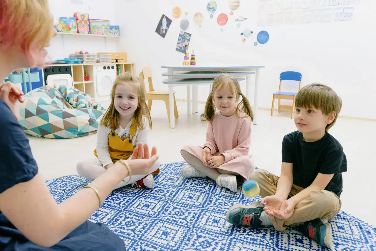 Kinder lernen im Kreis mit einer Lehrerin über den growth mindset grundschule. Sie sind auf einer blauen Decke.