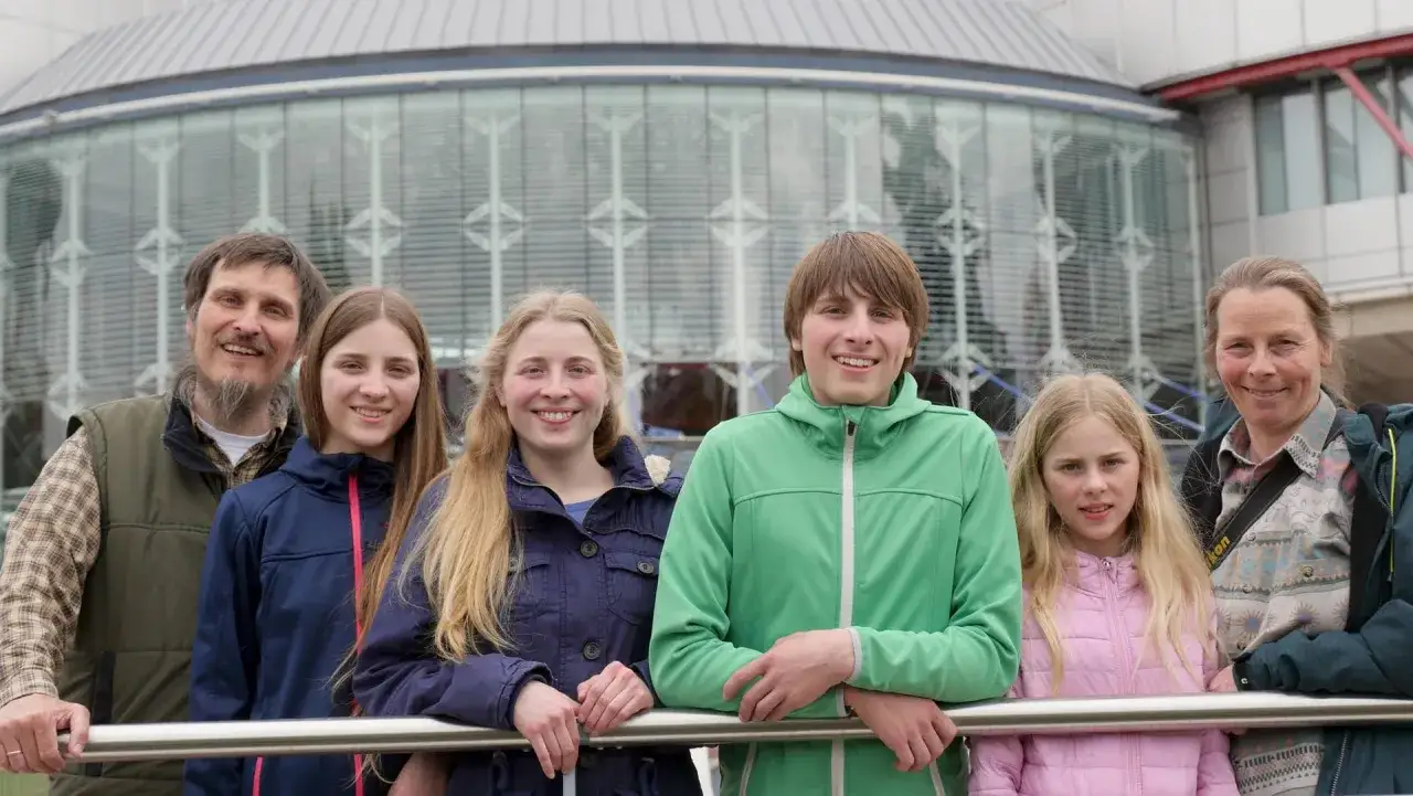 Glückliche Familie, die sich dem Homeschooling widmet, posiert vor einem modernen Gebäude.