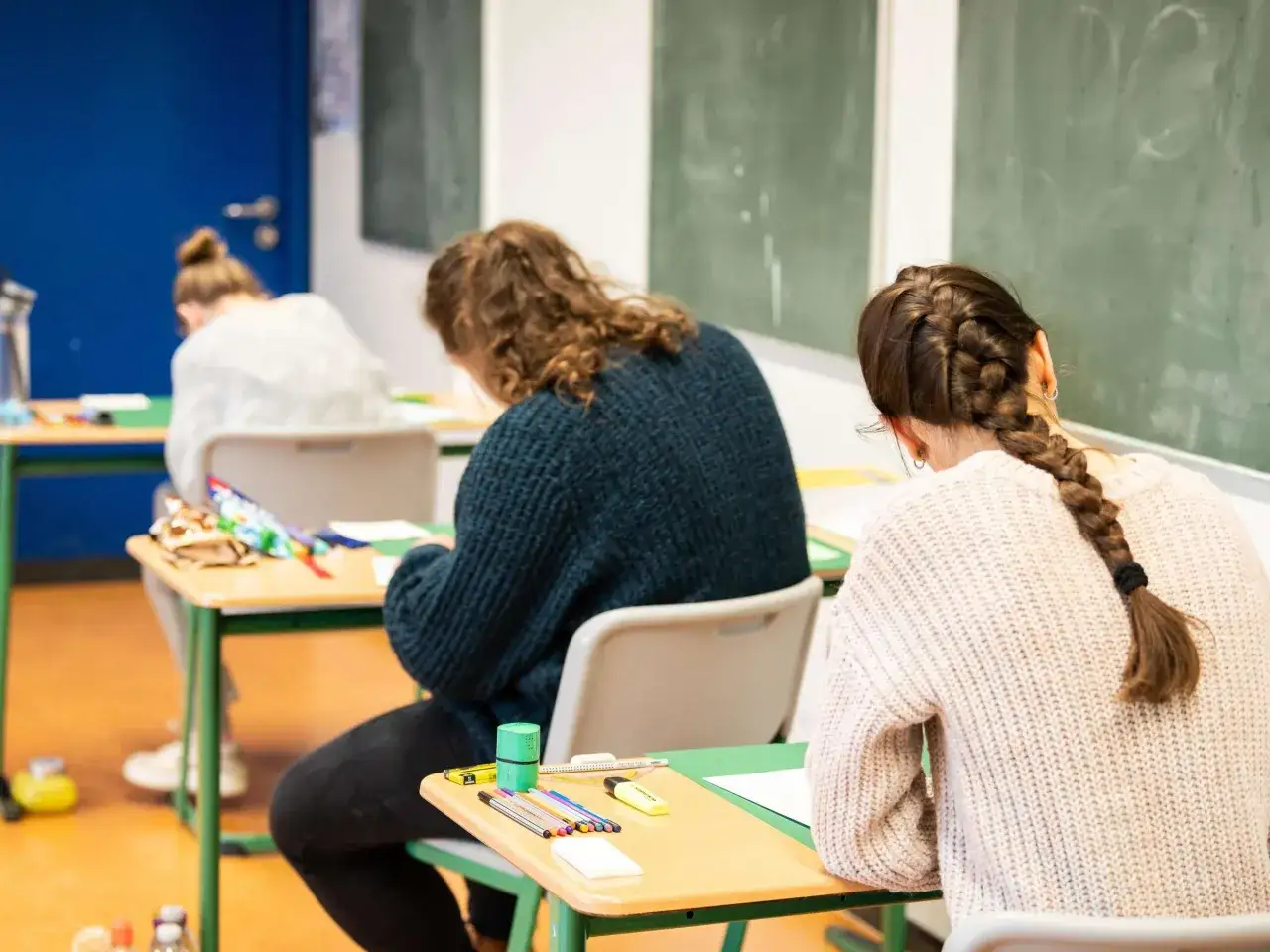 Schülerinnen konzentrieren sich auf ihre Arbeit im Klassenzimmer. Bald steht das Abitur an, eine wichtige Prüfung.