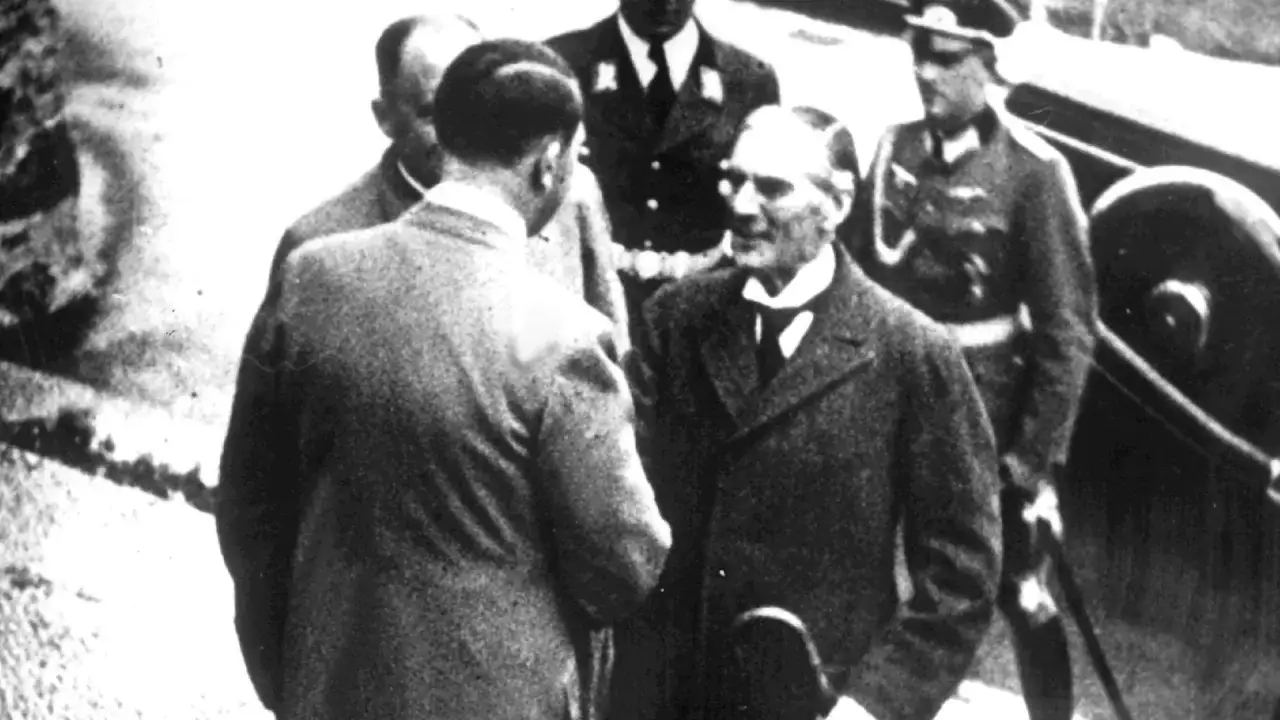 Männer in Anzügen und Uniformen, ein Treffen, das an die Appeasement-Politik erinnert.