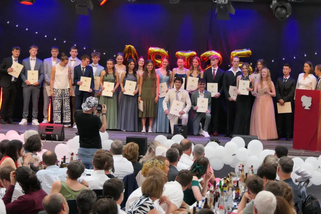 Absolventen erhalten Urkunden auf der Bühne. Der abiball ablauf wird mit Stolz gefeiert.