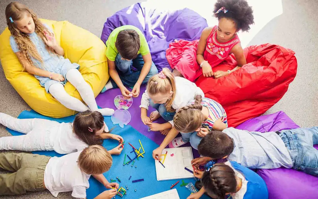 Kinder bauen mit Magnetbausteinen, ein Beispiel für freinet pädagogik, auf bunten Sitzsäcken.