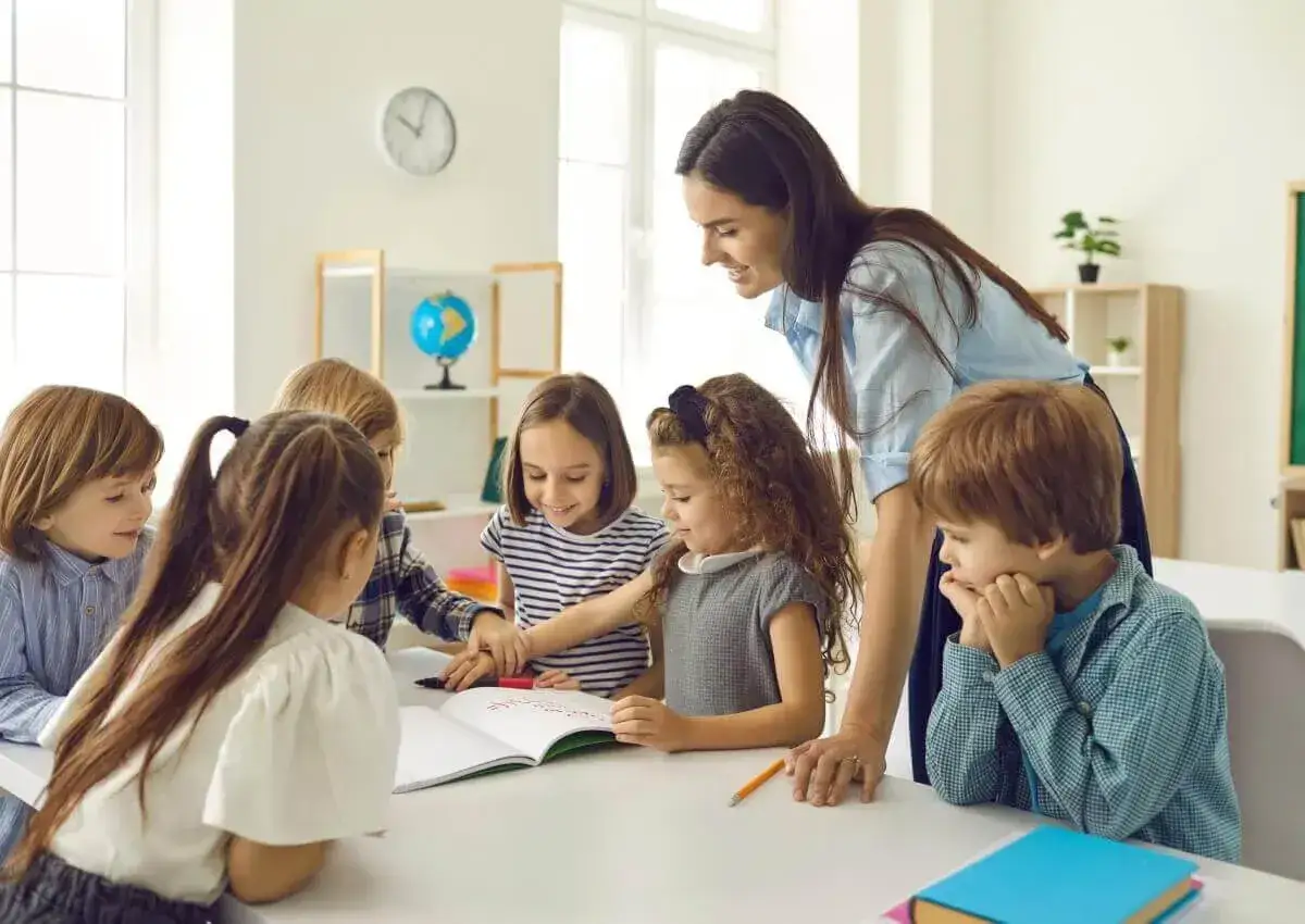 Lehrerin unterstützt Kinder bei einem spannenden Projektunterricht. Sie arbeiten gemeinsam an einem Heft.