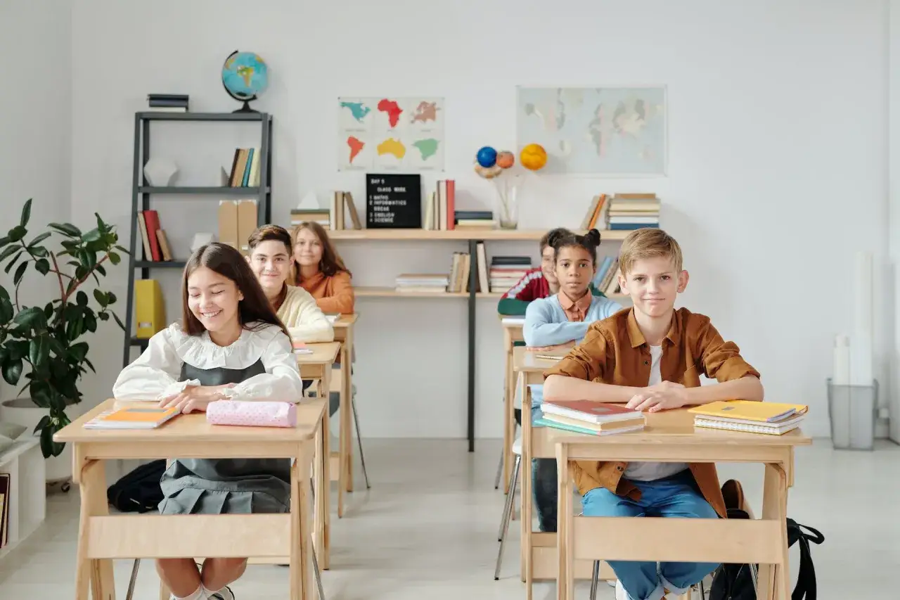 Schüler sitzen an Holztischen in einem Klassenzimmer. Eine gute Sitzordnung für unruhige Klassen könnte helfen, die Konzentration zu fördern.