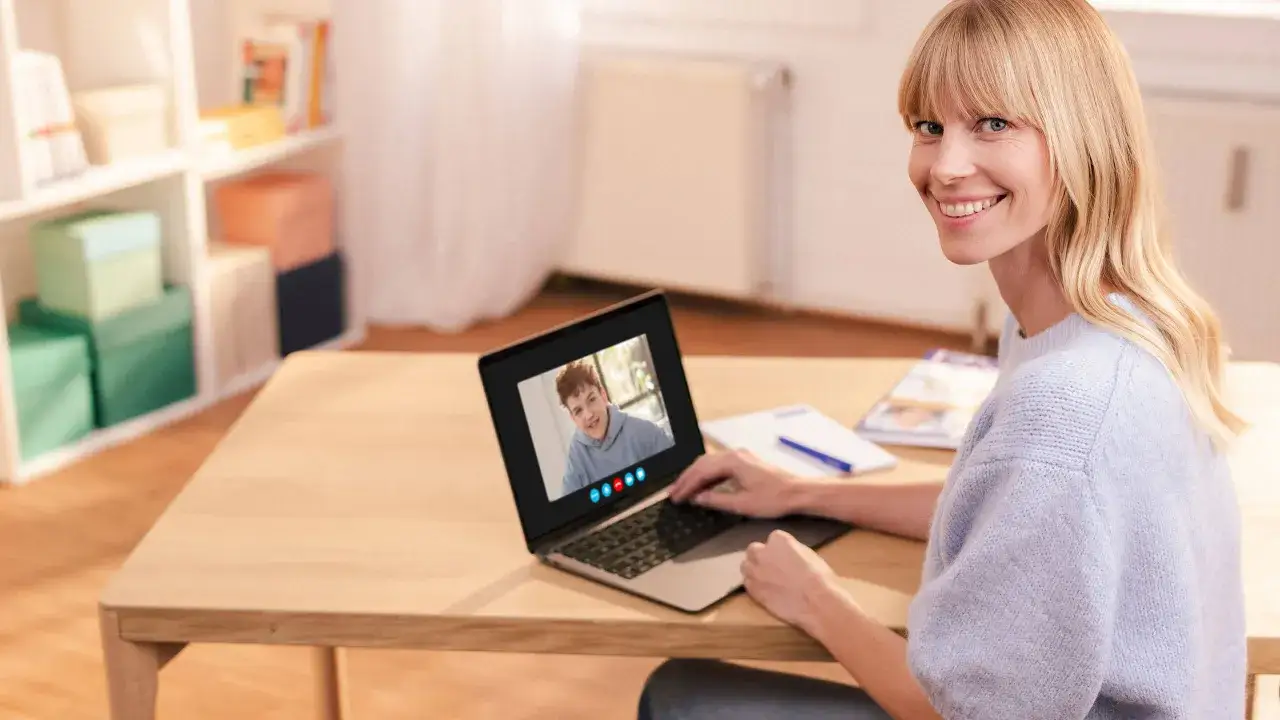 Eine Frau lächelt in die Kamera, während sie per Videoanruf mit einem Jungen spricht. Dies ist ein Beispiel für modernen Einzelunterricht.