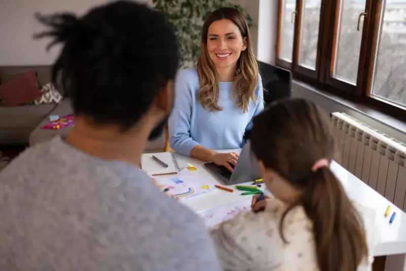 Lehrerin bespricht mit Eltern und Kind Fortschritte. Eine Elternsprechtag Vorlage für Lehrer könnte hier nützlich sein.